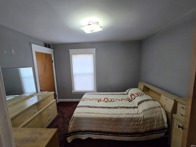 bedroom with dark carpet and baseboards