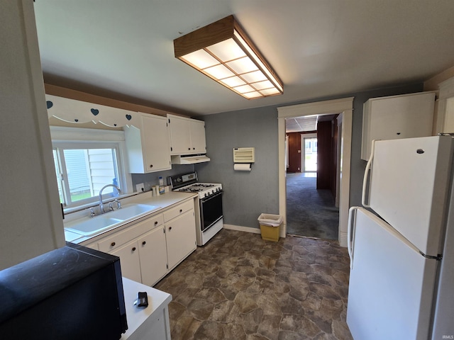 kitchen with white appliances, a sink, white cabinets, stone finish flooring, and under cabinet range hood