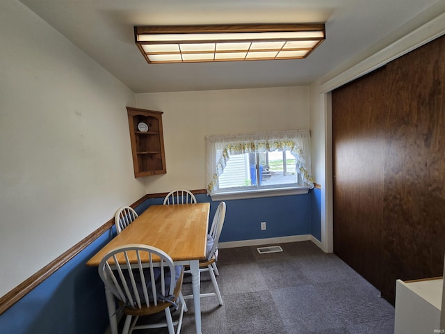 dining room featuring dark carpet and baseboards