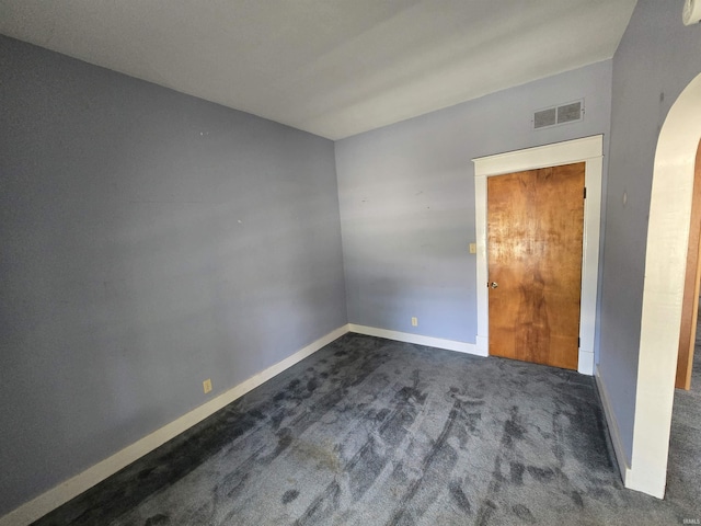 unfurnished room with arched walkways, carpet flooring, and baseboards