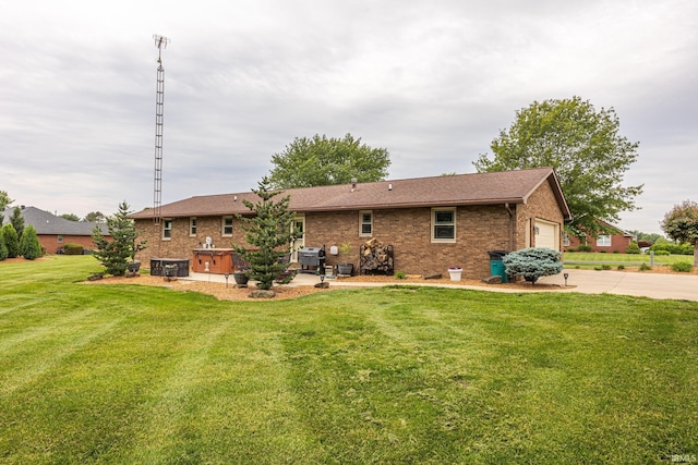 1376 N Hayland Dr, Jasper, IN 47546 - back of property featuring brick siding, a lawn, an attached garage, driveway, and a patio