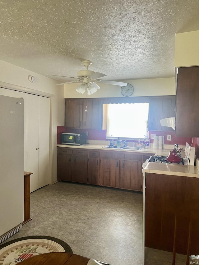 509 E Vincennes St, Orleans, IN 47452 - kitchen with a sink, freestanding refrigerator, a ceiling fan, light countertops, and a textured ceiling