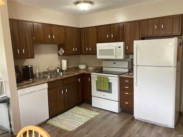 404 W Harrison Sts, Monticello, IN 47960 - kitchen with white appliances, a sink, dark wood finished floors, dark countertops, and dark brown cabinets