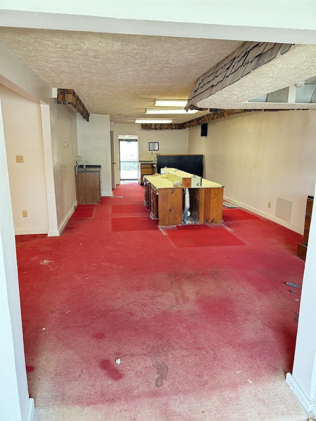 basement with carpet, baseboards, and a textured ceiling