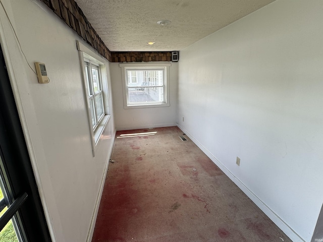 unfurnished room featuring baseboards, healthy amount of natural light, a textured ceiling, and concrete flooring