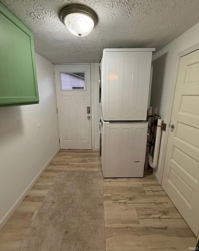 2146 N 20th St, Terre Haute, IN 47804 - laundry room featuring stacked washer and clothes dryer, cabinet space, baseboards, light wood-style floors, and a textured ceiling
