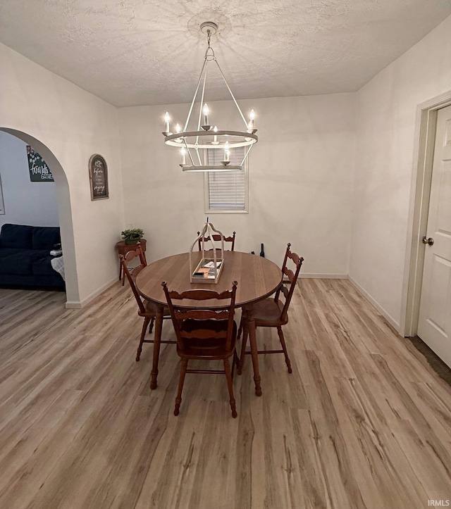 2146 N 20th St, Terre Haute, IN 47804 - dining area featuring arched walkways, a chandelier, light wood finished floors, a textured ceiling, and baseboards