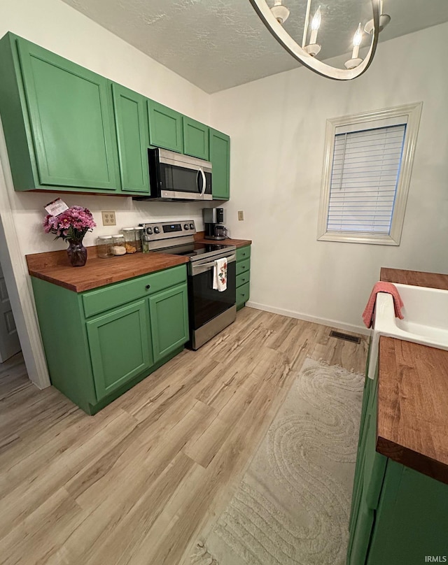 2146 N 20th St, Terre Haute, IN 47804 - kitchen with stainless steel appliances, butcher block countertops, green cabinets, and a chandelier