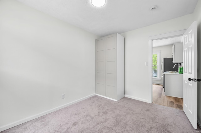 unfurnished bedroom featuring carpet floors, baseboards, and a sink