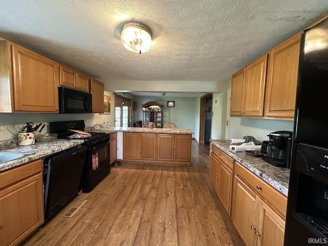 977 N Union Rd, Frankfort, IN 46041 - kitchen featuring black appliances, a peninsula, light wood-style floors, and a textured ceiling