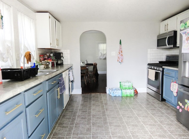 302 E Main St, Swayzee, IN 46986 - kitchen featuring appliances with stainless steel finishes, blue cabinets, arched walkways, backsplash, and light countertops