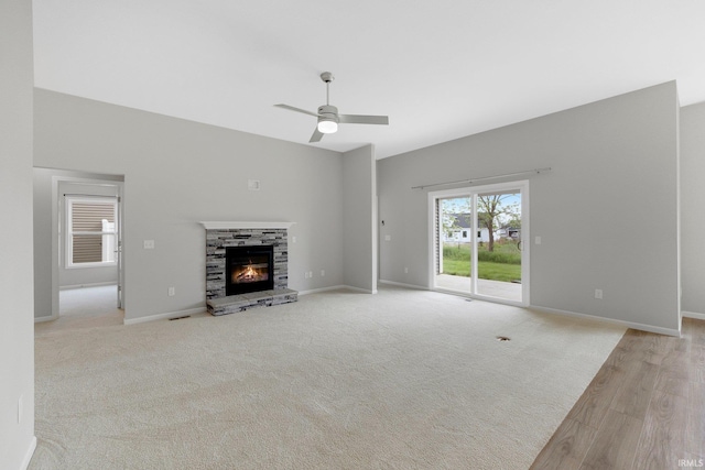 7696 Lila Way, Fort Wayne, IN 46835 - unfurnished living room featuring a stone fireplace, a ceiling fan, baseboards, and light wood finished floors