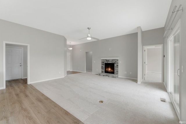 7696 Lila Way, Fort Wayne, IN 46835 - unfurnished living room featuring a ceiling fan, baseboards, a warm lit fireplace, and light wood-type flooring