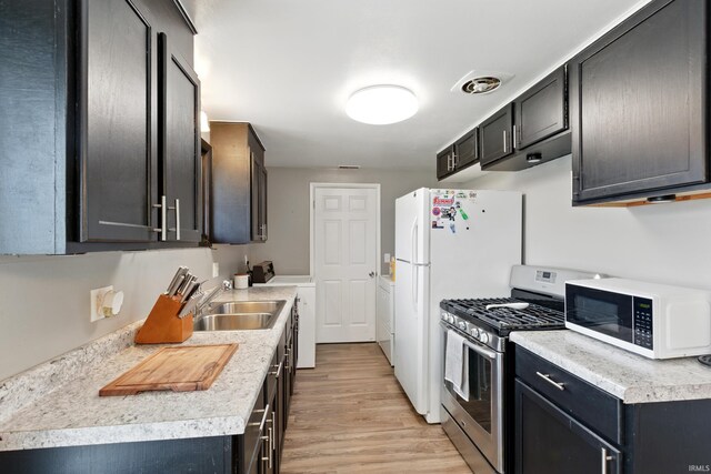 7205 Eby Rd, Fort Wayne, IN 46835 - kitchen featuring stainless steel gas range oven, white microwave, washer / dryer, a sink, and light wood finished floors
