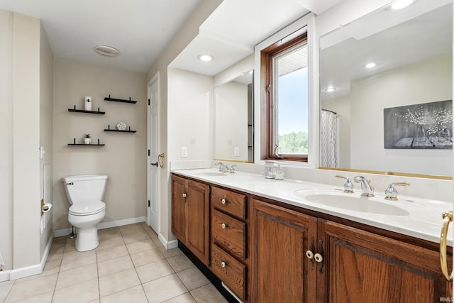 bathroom with toilet, tile patterned flooring, double vanity, and baseboards