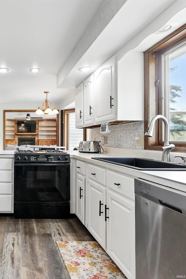 kitchen with stainless steel dishwasher, black gas range, a sink, and plenty of natural light
