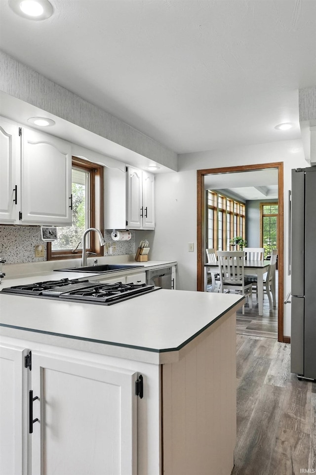 kitchen featuring freestanding refrigerator, light wood-type flooring, white cabinetry, a peninsula, and light countertops