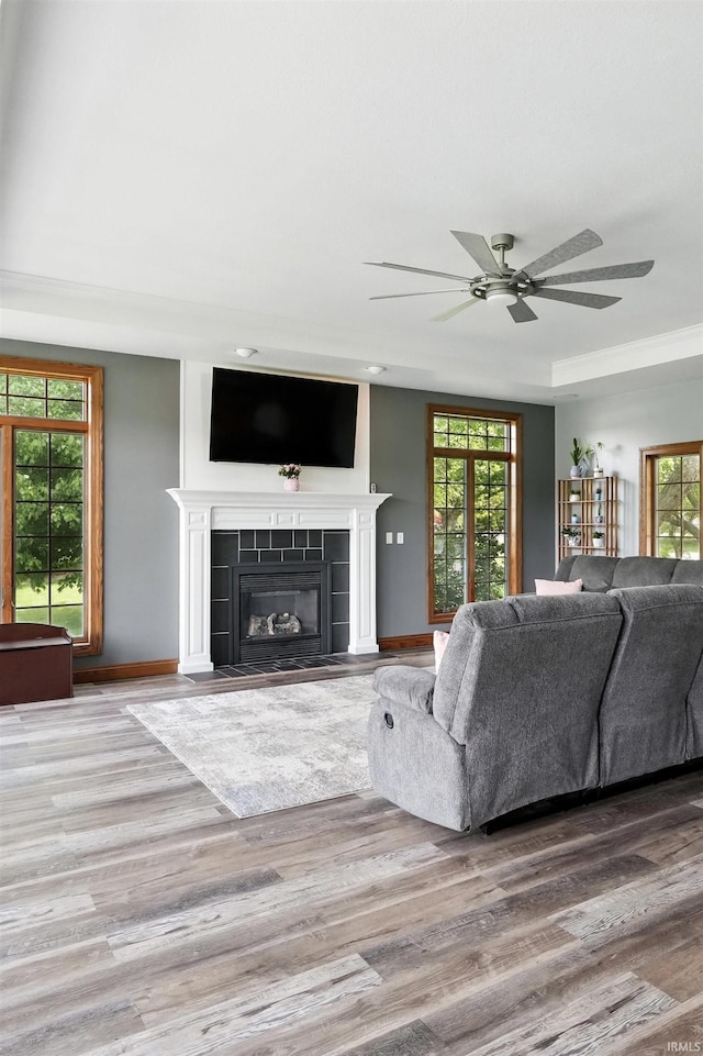 living area with wood finished floors, plenty of natural light, a ceiling fan, and a fireplace