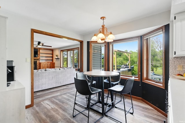 dining space with healthy amount of natural light, a chandelier, light wood-style flooring, and baseboards