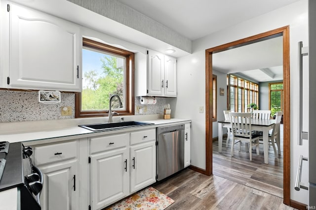 kitchen with dishwasher, a sink, black range with gas cooktop, light wood finished floors, and decorative backsplash