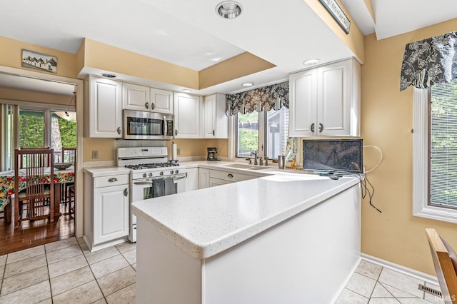 3455 Bridgetown Rd, Bristol, IN 46507 - kitchen featuring stainless steel microwave, white gas stove, white cabinetry, and light tile patterned floors