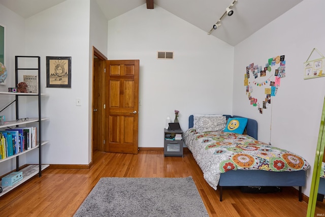bedroom featuring wood finished floors, baseboards, high vaulted ceiling, and beam ceiling