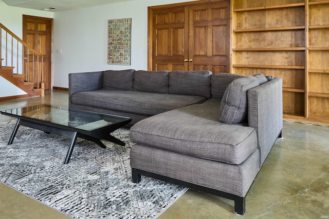 living room featuring finished concrete flooring and stairway