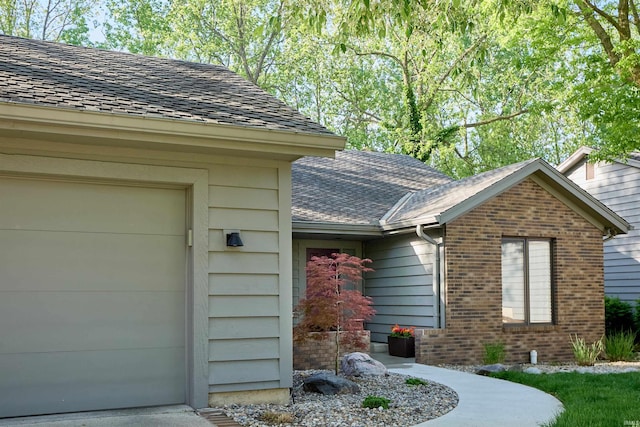 doorway to property with an attached garage and brick siding
