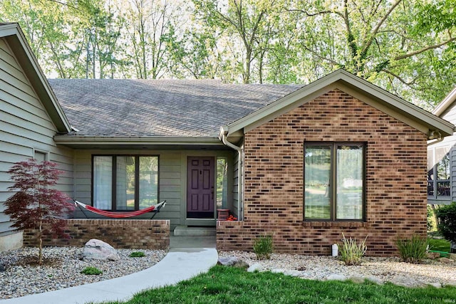 single story home featuring roof with shingles and brick siding