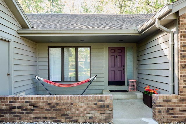 view of exterior entry with a shingled roof