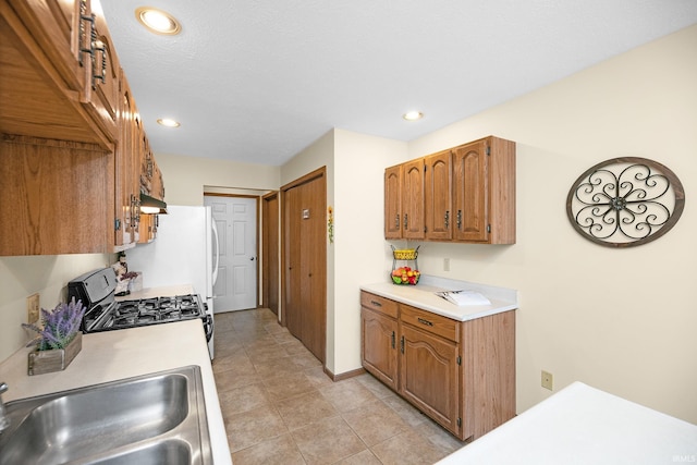 1600 Blue Heron Way S, Bend, IN 46628 - kitchen with gas range, a sink, light countertops, under cabinet range hood, and brown cabinets