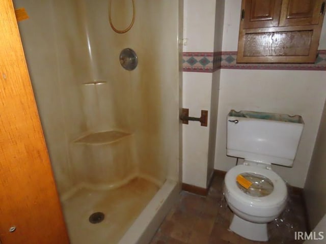 bathroom featuring a shower stall, toilet, and baseboards