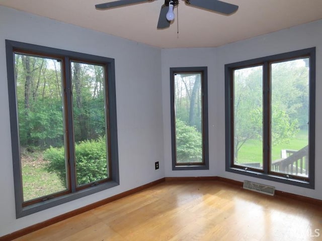 unfurnished room with healthy amount of natural light, baseboards, light wood finished floors, and a ceiling fan