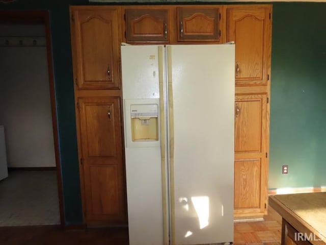 kitchen with white fridge with ice dispenser, light countertops, and brown cabinetry