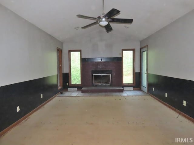 unfurnished living room featuring lofted ceiling, a fireplace, baseboards, and a ceiling fan