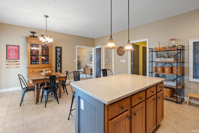 3934 Rushgrove Dr, Lafayette, IN 47909 - kitchen with light tile patterned floors, a chandelier, hanging light fixtures, a kitchen island, and baseboards
