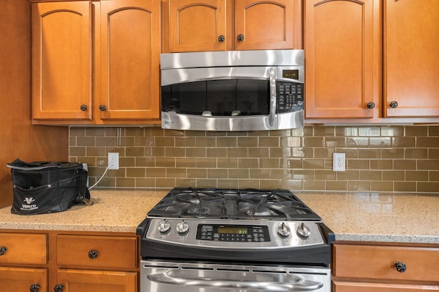 3934 Rushgrove Dr, Lafayette, IN 47909 - kitchen with appliances with stainless steel finishes, decorative backsplash, brown cabinets, and light stone countertops