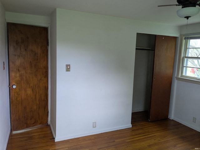 unfurnished bedroom with a closet, wood finished floors, baseboards, and a ceiling fan