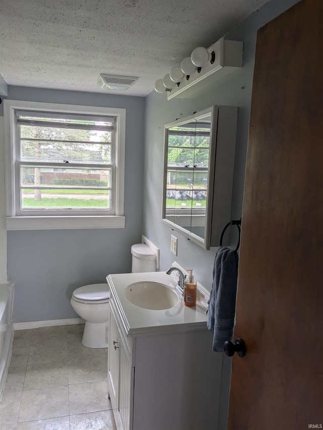 full bathroom with toilet, vanity, tile patterned flooring, a tub to relax in, and baseboards