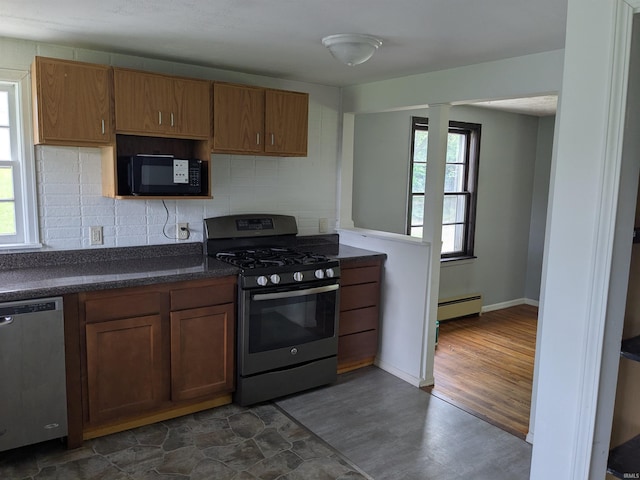 kitchen with stainless steel appliances, a baseboard radiator, dark countertops, dark wood-style floors, and decorative backsplash