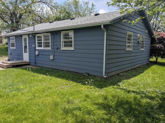 back of house featuring a shingled roof and a yard