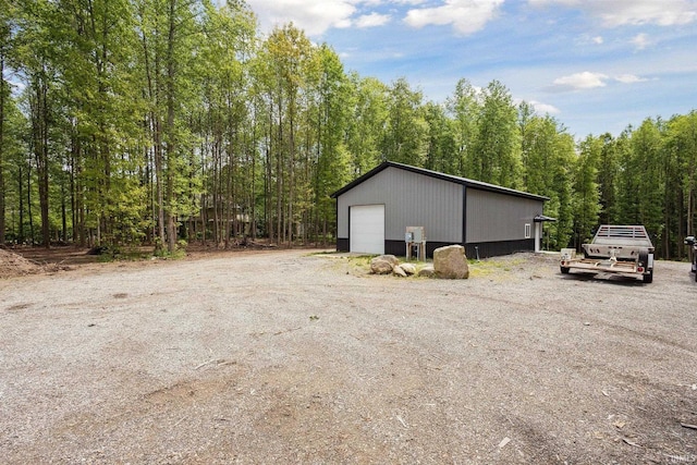 7428 E 400 N Rd, Rolling Prairie, IN 46371 - view of side of home with a detached garage, an outdoor structure, and a forest view