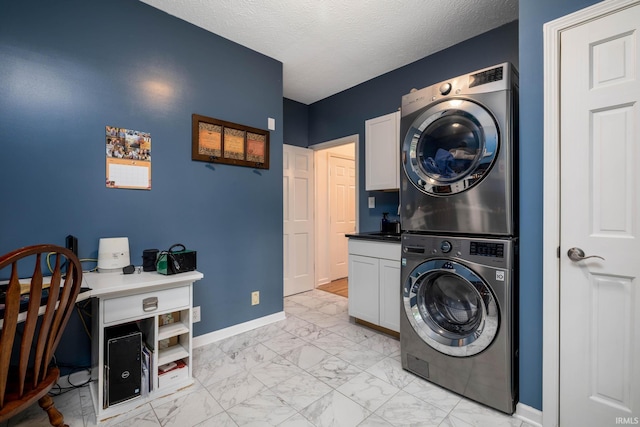 9838 Gulfstream Ct, Fishers, IN 46037 - washroom featuring stacked washer / drying machine, cabinet space, light marble finish floors, baseboards, and a textured ceiling