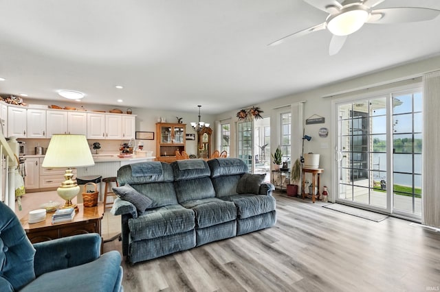 living area with healthy amount of natural light, ceiling fan, a chandelier, light wood-type flooring, and recessed lighting