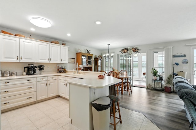 kitchen with a peninsula, a breakfast bar, a sink, light countertops, and a chandelier