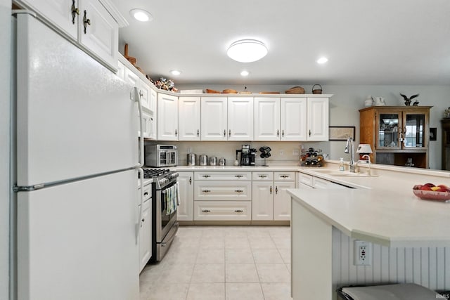 kitchen featuring white appliances, a peninsula, a sink, light countertops, and white cabinetry