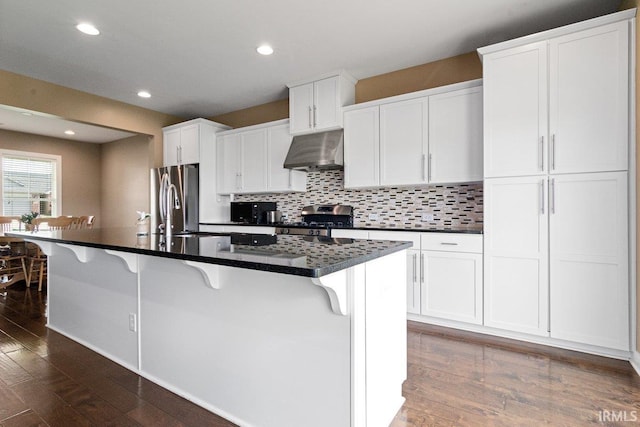 3102 Paradise Cir, Newburgh, IN 47630 - kitchen featuring under cabinet range hood, stainless steel appliances, dark wood finished floors, a breakfast bar, and white cabinets