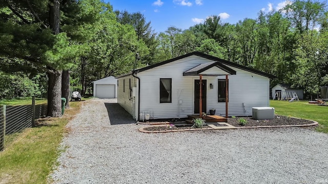view of front of home featuring driveway, an outbuilding, a detached garage, a front yard, and a playground
