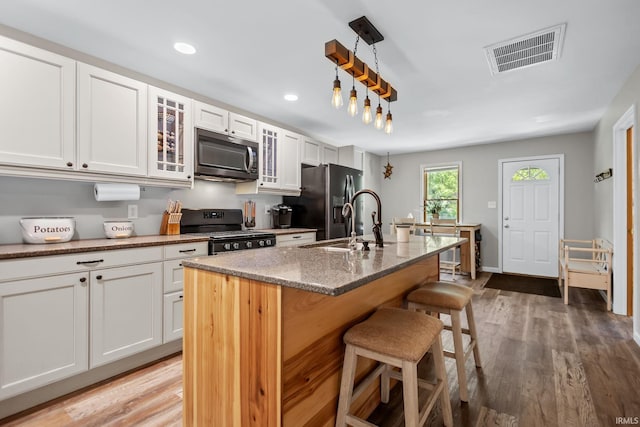 kitchen with appliances with stainless steel finishes, a kitchen bar, white cabinetry, and recessed lighting