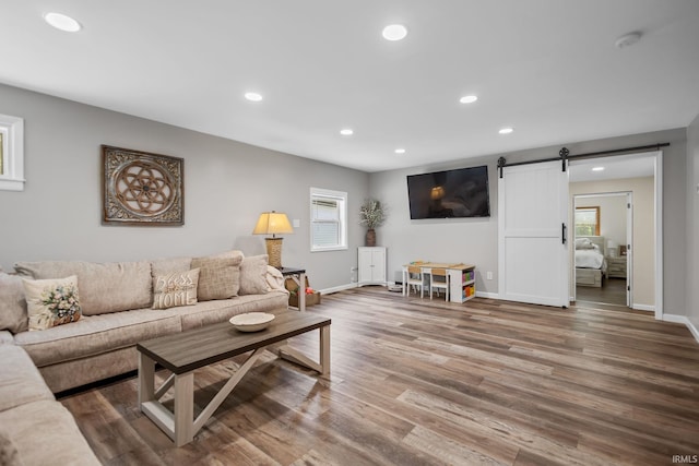 living area with a barn door, healthy amount of natural light, wood finished floors, recessed lighting, and baseboards